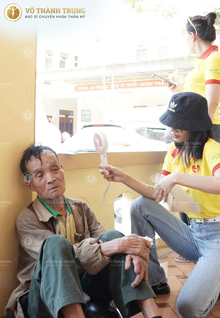 Một thành viên torng đoàn thiện nguyện đang quạt cho một cụ già mệt mỏi