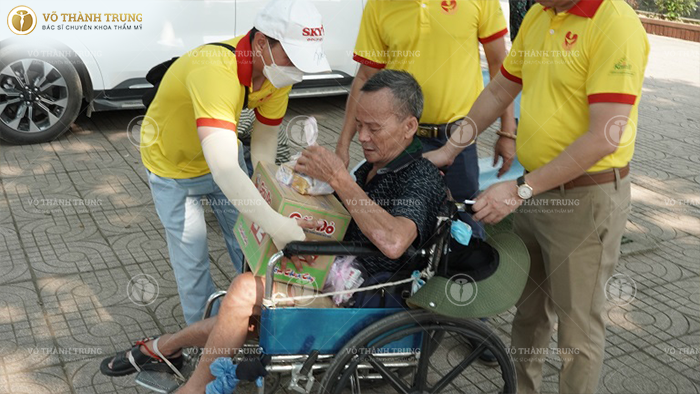 Một cụ già bị tật đang được đoàn thiện nguyện trao quà
